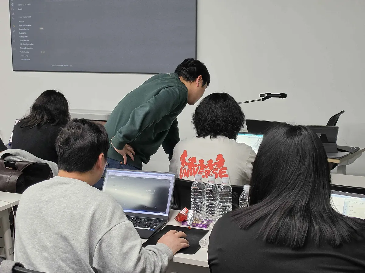 강사가 수강생 자리에서 노트북 화면을 함께 보는 장면